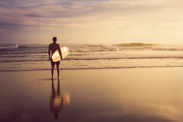 ToF Behang sport man met surfplank op het strand met zonsondergang